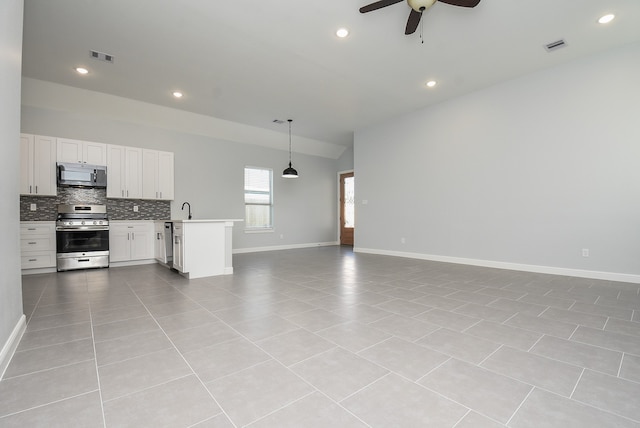 kitchen with kitchen peninsula, white cabinets, light tile patterned floors, appliances with stainless steel finishes, and vaulted ceiling