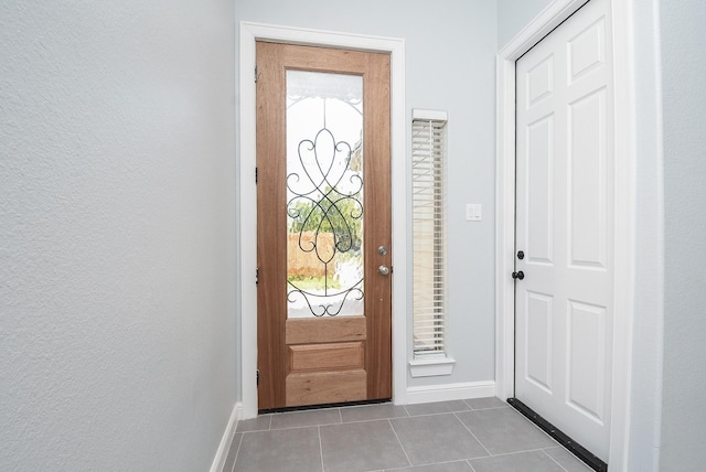 foyer entrance with baseboards, tile patterned floors, and plenty of natural light