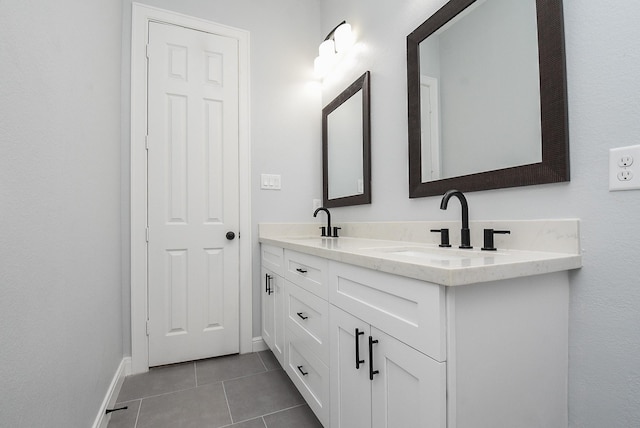 full bath featuring tile patterned flooring, a sink, double vanity, and baseboards