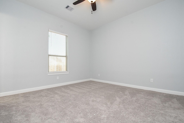 carpeted spare room with baseboards, visible vents, and a ceiling fan