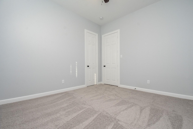 carpeted spare room featuring ceiling fan and baseboards
