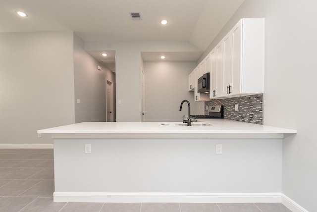 kitchen featuring a sink, black microwave, visible vents, a peninsula, and gas stove