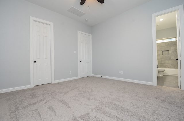 unfurnished bedroom featuring ensuite bath, light carpet, a closet, and ceiling fan