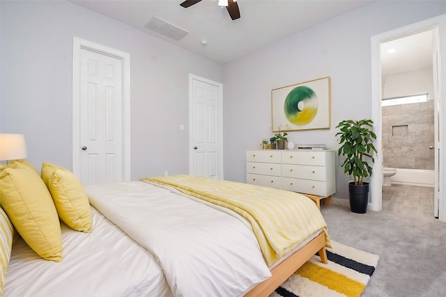 carpeted bedroom with ceiling fan, visible vents, connected bathroom, and baseboards