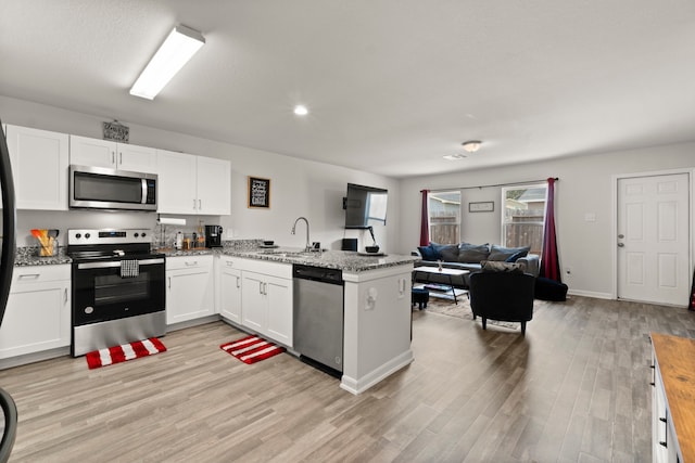 kitchen with light hardwood / wood-style floors, stainless steel appliances, kitchen peninsula, and white cabinetry