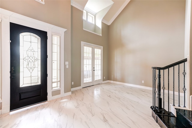 foyer with a high ceiling, ornamental molding, and french doors