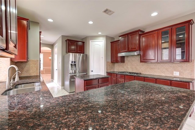 kitchen with dark stone counters, tasteful backsplash, sink, a kitchen island, and stainless steel appliances