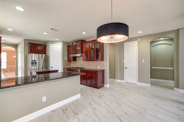 kitchen with dark stone countertops, pendant lighting, stainless steel appliances, and tasteful backsplash