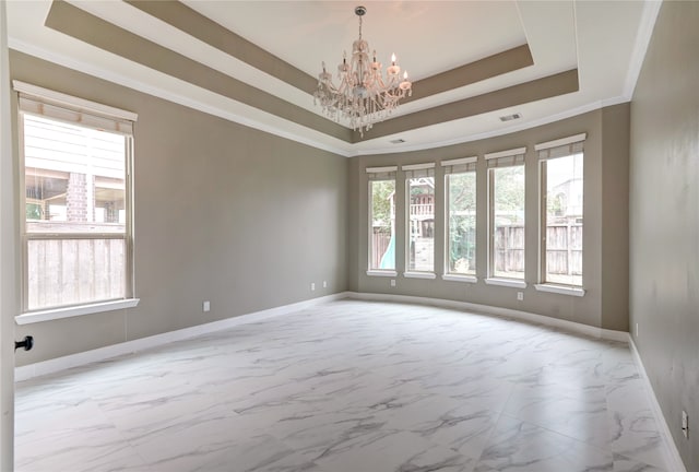 spare room with ornamental molding, a chandelier, and a tray ceiling