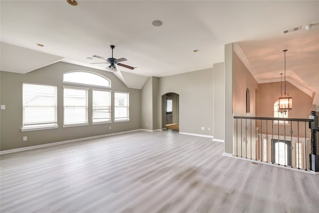 empty room with ceiling fan with notable chandelier, vaulted ceiling, and light hardwood / wood-style flooring