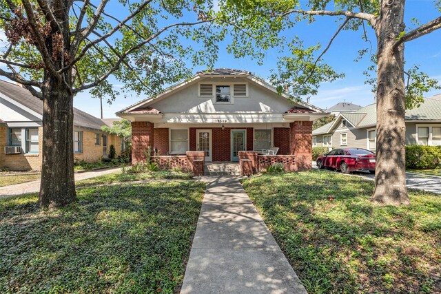 bungalow-style house featuring a front lawn, cooling unit, and a porch