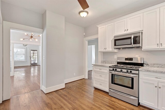 kitchen featuring a chandelier, white cabinetry, stainless steel appliances, and light stone counters