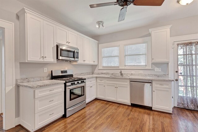 kitchen with sink, stainless steel appliances, white cabinetry, and light hardwood / wood-style flooring