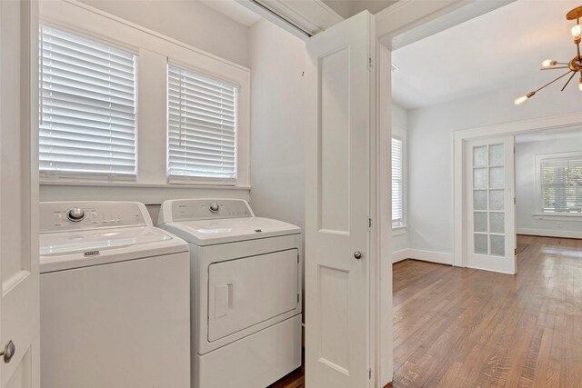 laundry area featuring separate washer and dryer, hardwood / wood-style flooring, and a notable chandelier