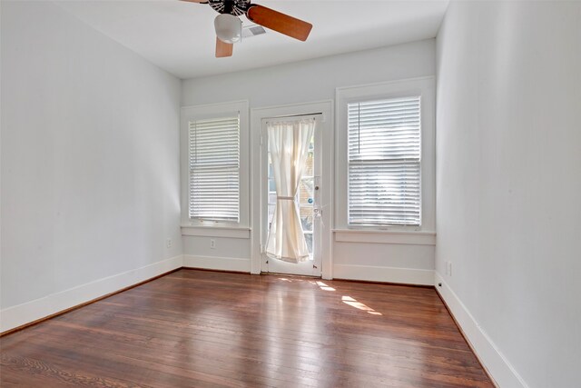 empty room featuring dark wood-type flooring, ceiling fan, and a healthy amount of sunlight