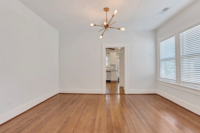 spare room with light wood-type flooring and a notable chandelier