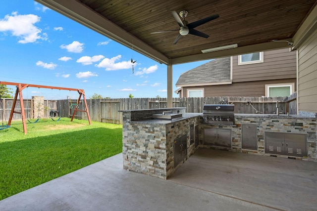 view of patio / terrace with ceiling fan, a playground, grilling area, and exterior kitchen