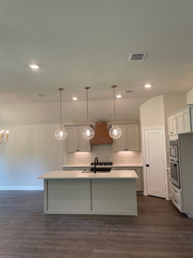 kitchen featuring pendant lighting, dark hardwood / wood-style floors, sink, and a kitchen island with sink