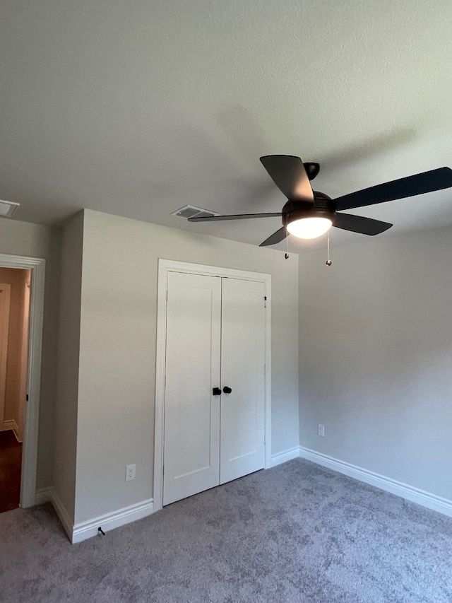 unfurnished bedroom with carpet flooring, ceiling fan, a closet, and a textured ceiling