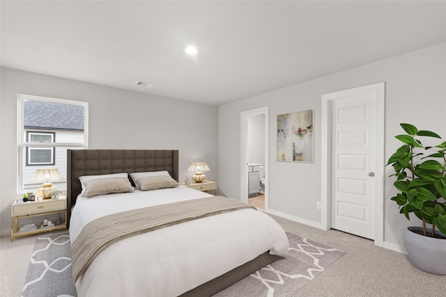 bedroom featuring light colored carpet and ensuite bath