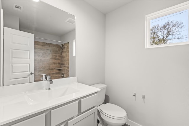 bathroom with toilet, vanity, and tiled shower