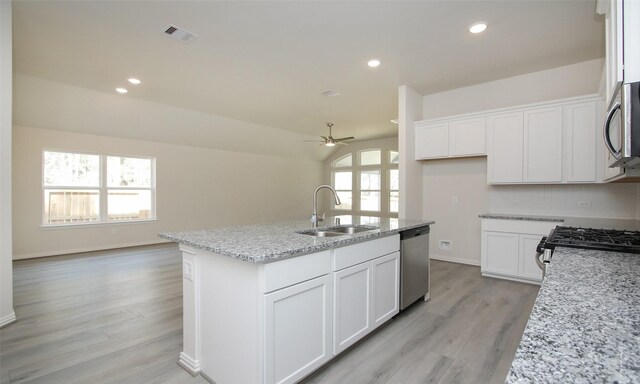 kitchen with light stone counters, ceiling fan, an island with sink, sink, and appliances with stainless steel finishes