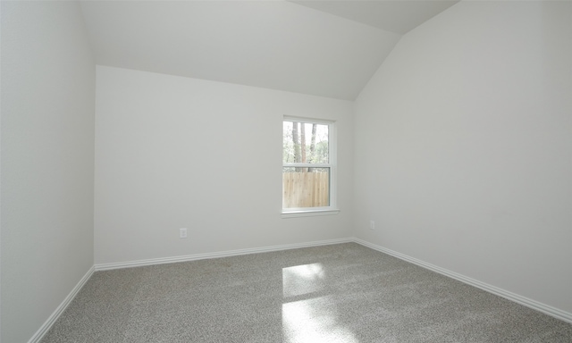 spare room featuring carpet and vaulted ceiling