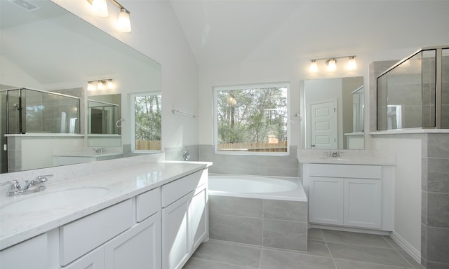 bathroom with plus walk in shower, vaulted ceiling, tile patterned flooring, and vanity