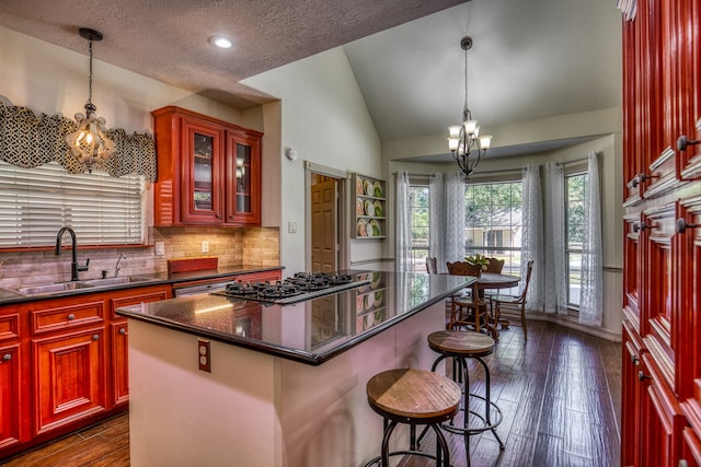 kitchen with a chandelier, pendant lighting, a kitchen island, sink, and lofted ceiling