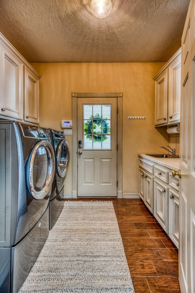 clothes washing area with sink, washing machine and dryer, and cabinets