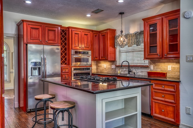 kitchen featuring stainless steel appliances, sink, a breakfast bar area, dark hardwood / wood-style flooring, and pendant lighting