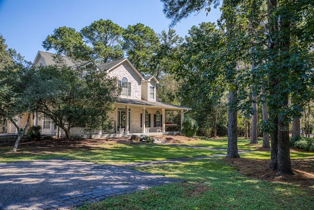 farmhouse inspired home featuring a porch and a front lawn