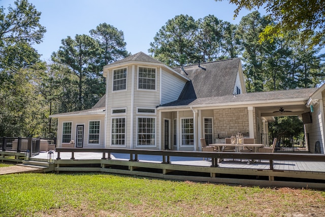 rear view of property with ceiling fan, a wooden deck, and a lawn