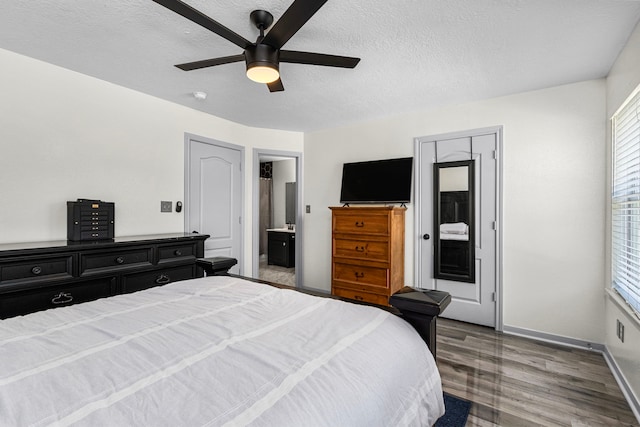 bedroom with ceiling fan, a textured ceiling, ensuite bath, and wood-type flooring