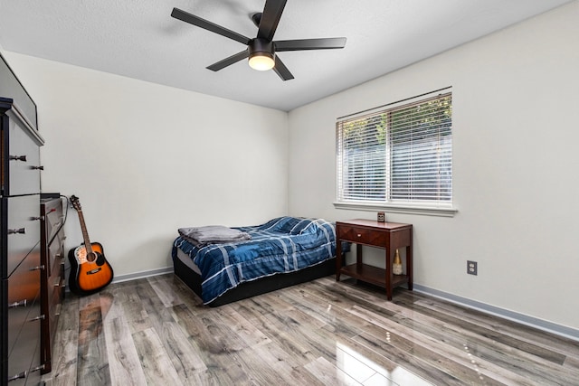 bedroom with ceiling fan, hardwood / wood-style floors, and a textured ceiling