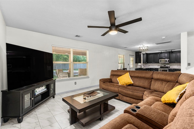 living room featuring ceiling fan, sink, and a textured ceiling