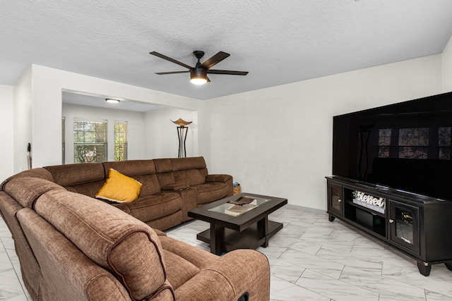 living room featuring ceiling fan and a textured ceiling