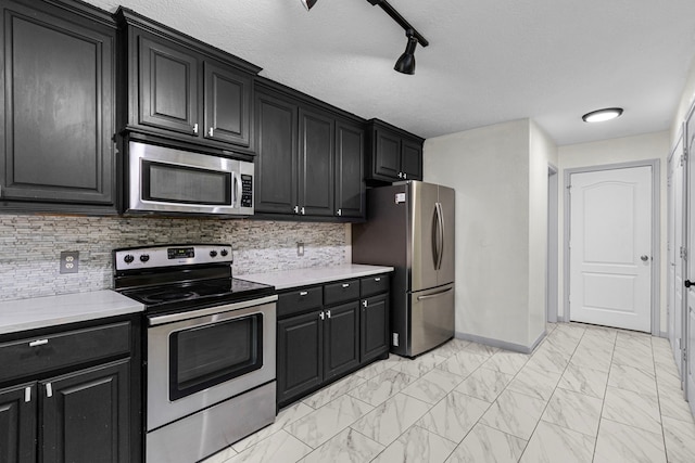 kitchen with a textured ceiling, stainless steel appliances, track lighting, and tasteful backsplash