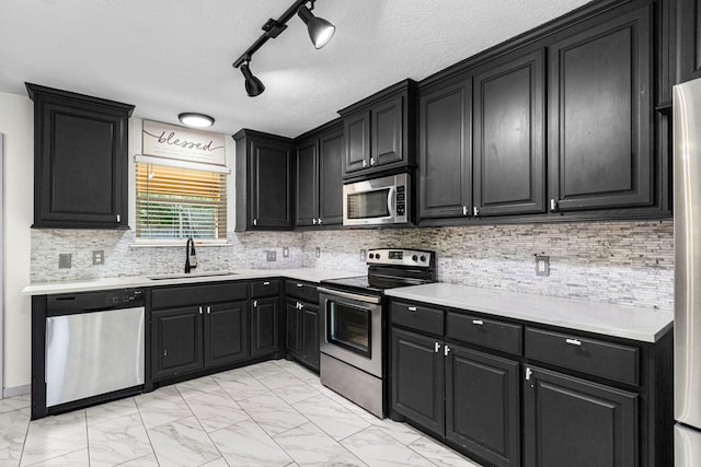 kitchen with track lighting, a textured ceiling, stainless steel appliances, and sink