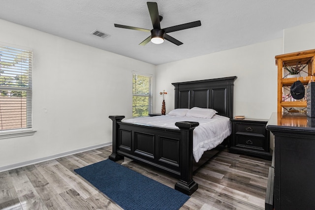 bedroom with ceiling fan, a textured ceiling, and dark hardwood / wood-style floors