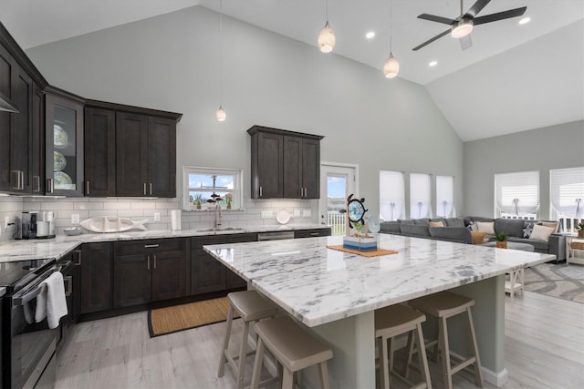 kitchen with ceiling fan, light hardwood / wood-style flooring, backsplash, high vaulted ceiling, and a center island