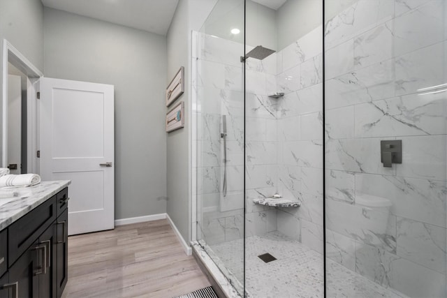 bathroom featuring wood-type flooring, vanity, and a tile shower