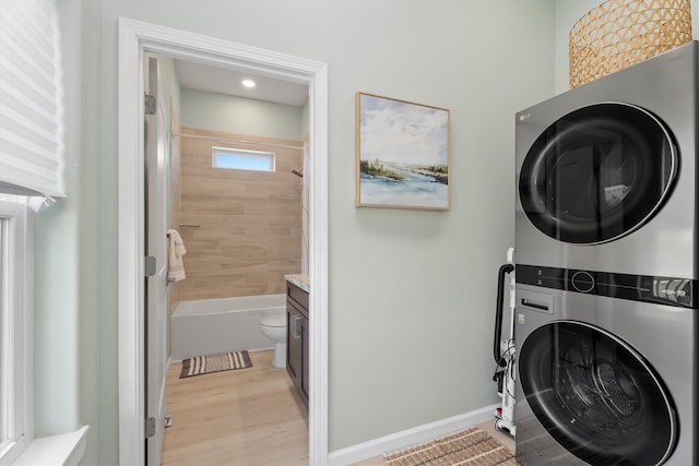 laundry room featuring stacked washer and clothes dryer and light hardwood / wood-style floors