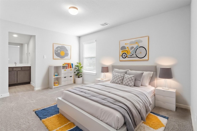 bedroom featuring light colored carpet, a sink, visible vents, baseboards, and ensuite bath