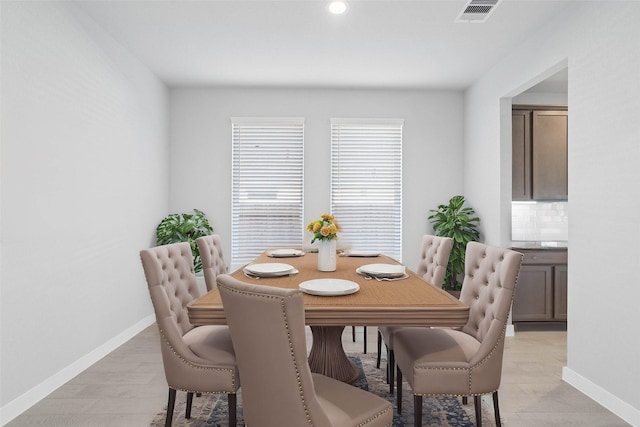 dining space with light wood-type flooring, visible vents, and baseboards