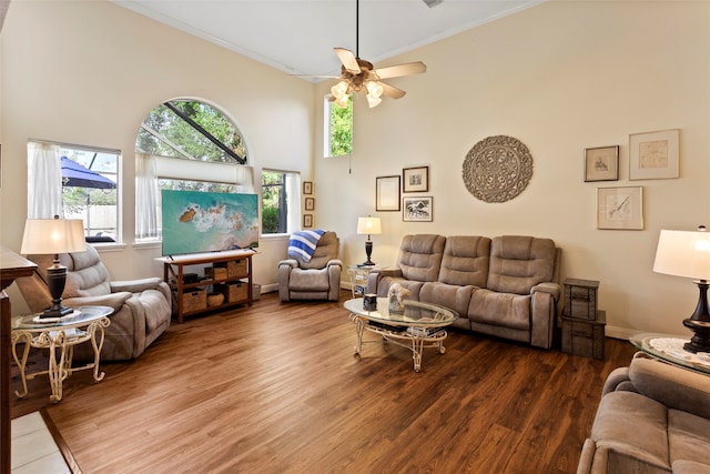 living room featuring a towering ceiling, ceiling fan, hardwood / wood-style flooring, and crown molding