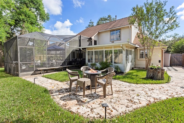 back of house with a patio, a lawn, glass enclosure, and an outdoor fire pit