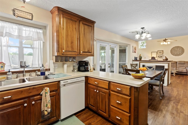 kitchen with dishwasher, a textured ceiling, dark wood-type flooring, sink, and kitchen peninsula