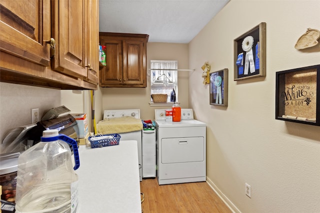 washroom featuring separate washer and dryer, cabinets, and light hardwood / wood-style floors