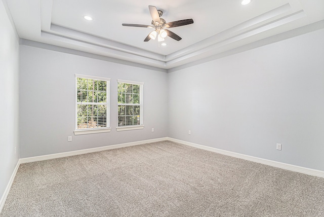 carpeted empty room with a tray ceiling and ceiling fan